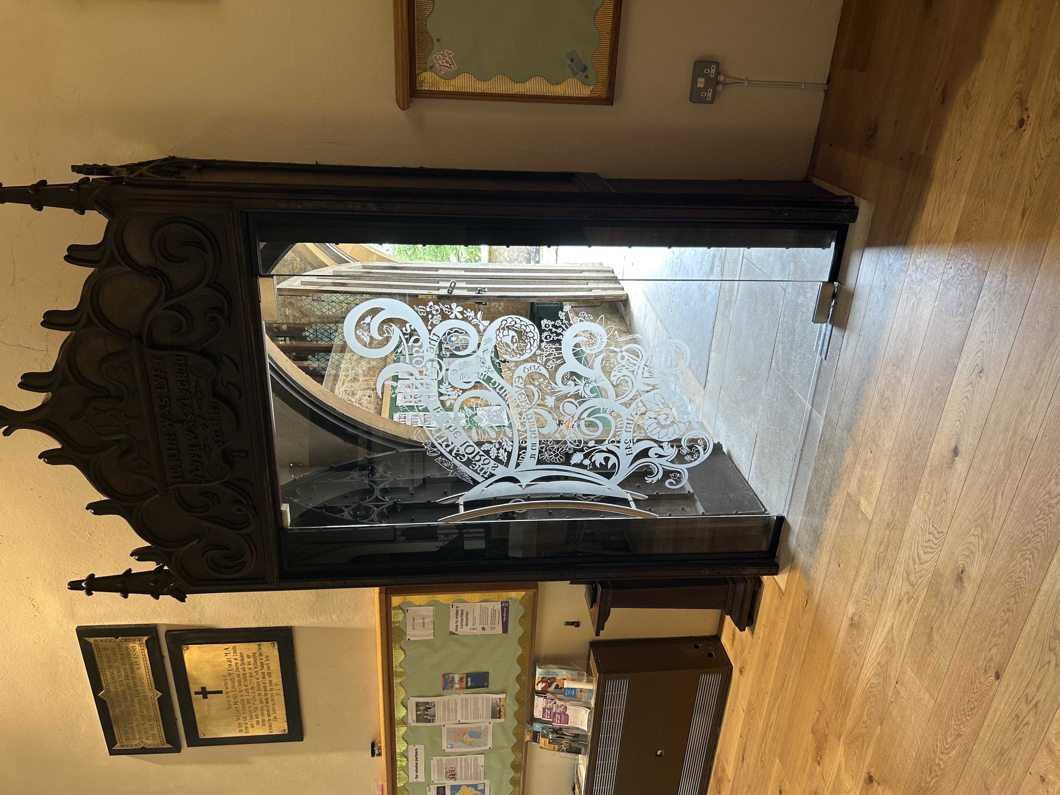 Church door with ancient wooden frame and modern glass insert with etched pattern
